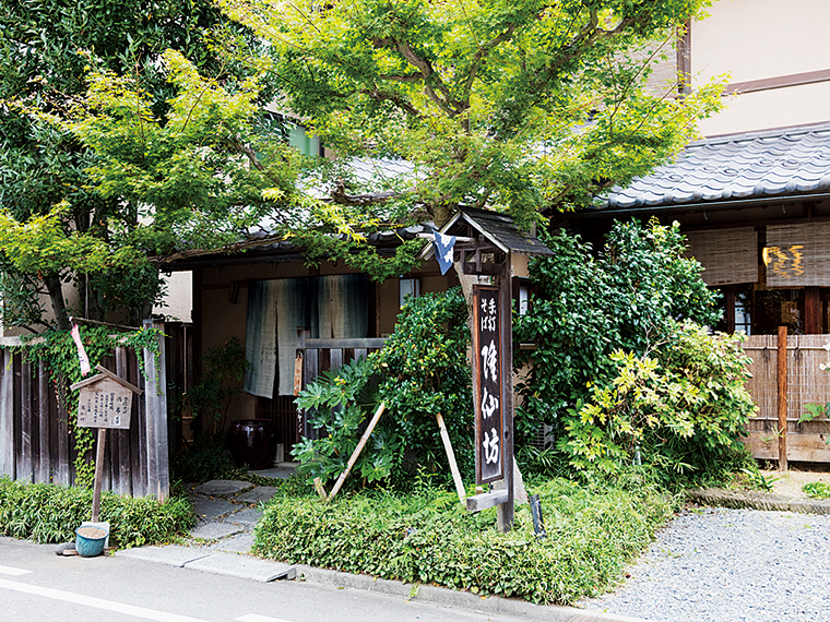 庭木とともに趣ある外観を呈す古民家風の店。店内にも掘りごたつ風の板の間、座敷などに民芸品などが飾られている。評判を聞き付け、これまで作家や落語家、料理人、俳優など多くの著名人も来店している