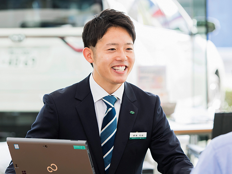 営業の峰島和哉さん。コミュニケーションのツボを学び、笑顔での接客も板についてきた