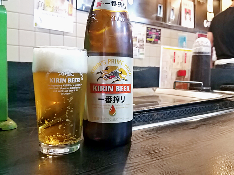 歴史の刻まれたカウンターの木目に映える瓶ビール（650円）