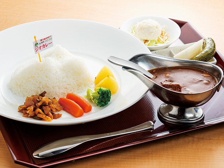 「ジオカレー 会津牛ゴロゴロ」(1,330円)。ポテトサラダ、自家製ピクルス、漬物付き。磐梯山をかたどったご飯のまわりには色とりどりの地物野菜が並ぶ。別添えのカレーには大きめの会津牛がたっぷり入っている。少し辛口ながらまろやかで深い味わいに食が進む