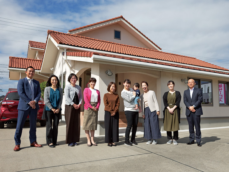 社屋前にて全員集合。育児休暇からの復帰手続きに訪れた社員も一緒に。右から3番目が安島社長