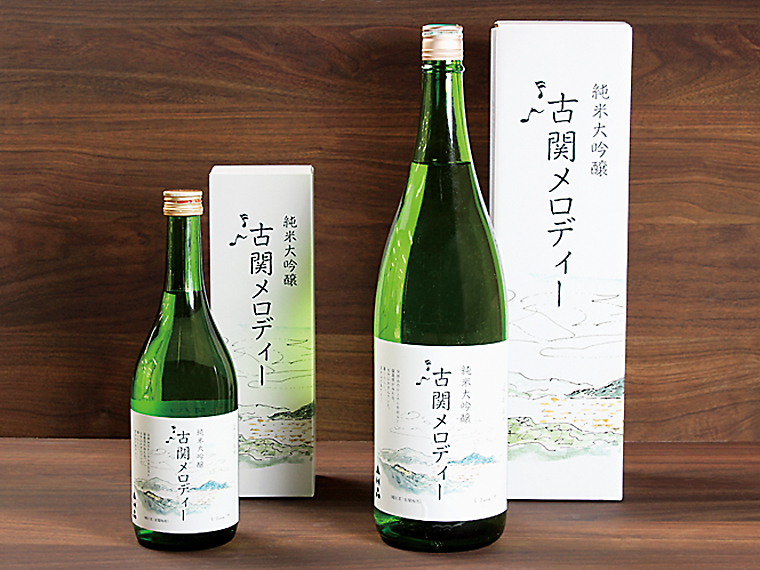 福島市唯一の造り酒屋「金水晶酒造店」の純米大吟醸「古関メロディー」（720ml・3,960円、1,800ml・6,930円）。福島独自米「福乃香」が原料。箱には先生自身の絵と文をあしらった