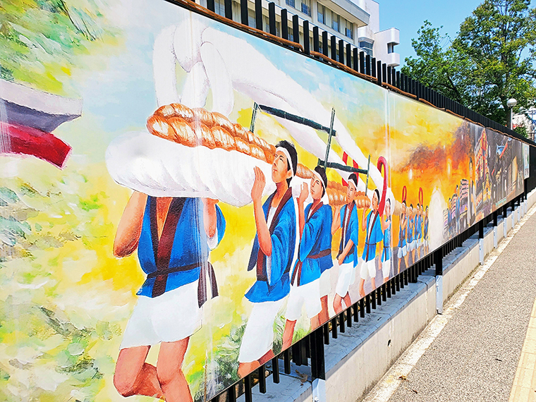 福島市内にある看板に描かれた「わらじまつり」のイラスト。「わらじ音頭」はこんな感じで「大わらじ」を担いで練り歩く夏まつりの時に流されます(2019年から、アレンジが加わった曲にリニューアルしています)