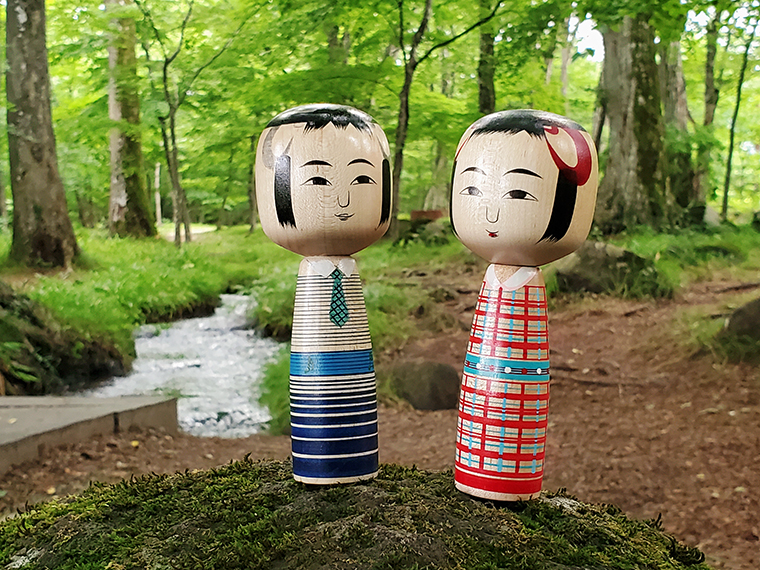 水林公園の一角、裕一が立っている場所あたり。土湯こけしの工人の一人・近藤明裕さんが古関裕而夫妻をイメージして作った「おしどりコケシ」を置いて撮影