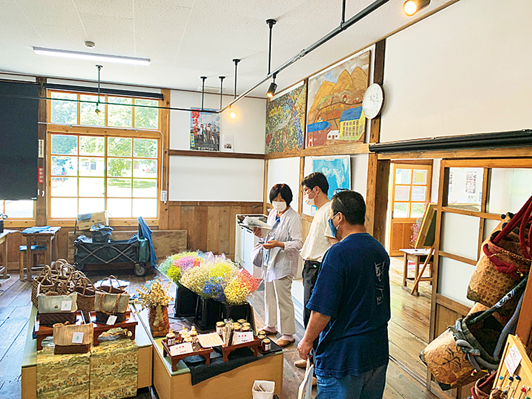 昭和村特産のからむし織、かごバッグ、カスミソウ、自然薯の商品などが並ぶ。他にも多ジャンルのお店が登場する。木造校舎の雰囲気も楽しもう