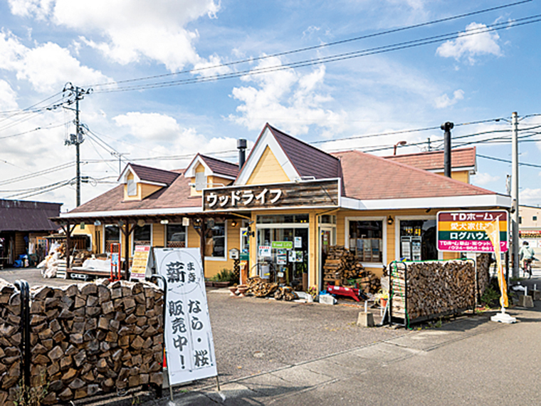 ショールーム外観。福島県内産の薪が多数積み上げられており、焚火用の少量の薪だけでも購入可能（2束相当16kg・税込1,100円～）