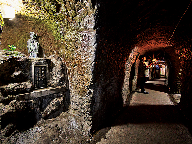 修験者たちが雨露をしのぐために掘った七つの洞窟は現在1本につなげられ、迷路のような「洞窟めぐり」が体験できる。洞内には不動明王に仕えた三十六童子像が祀られている