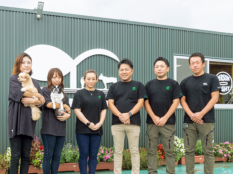 『パーソンライト』のおしゃれな社屋の前で奥様(左から3人目)とスタッフの皆さん、愛犬と一緒に