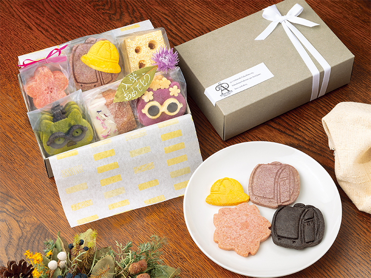 箱を開けた瞬間の笑顔が目に浮かぶ。ランドセル、帽子、桜のクッキーは4種類の組み合わせから選べる。添えられる葉には希望のメッセージを書いてもらえる