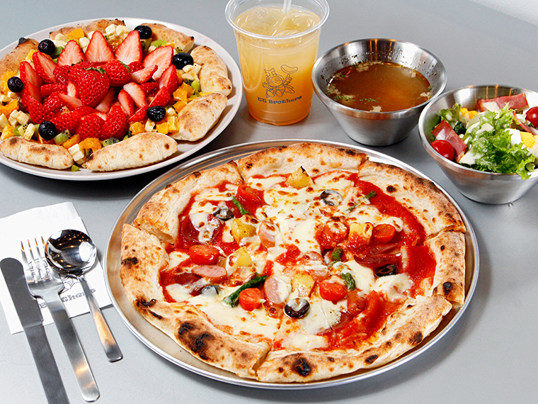 手前が4種類のトッピングを選べる「TT-pizza TT4」(2,035円)。標準サイズは直径約28cm。奥がフルーツピザ「ラ・フルッタ」。ピザには、スープと特製サラダが付く