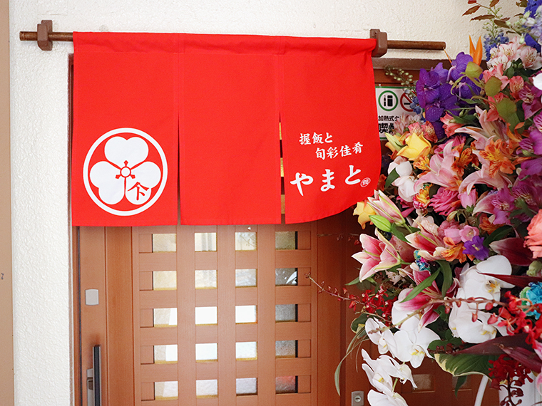 「MIYAKOビル」左横の階段を進んで奥に店舗がある。赤い暖簾が目印