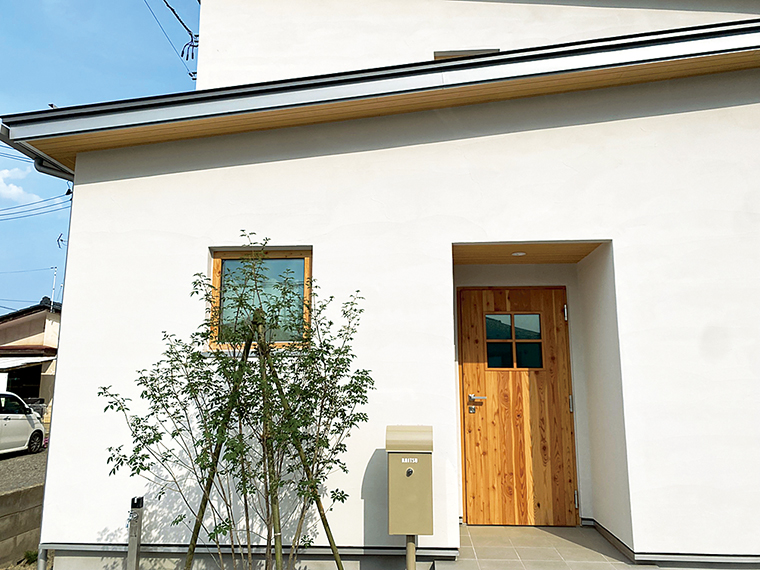 木製ドアと緑の調和が美しい玄関づくり