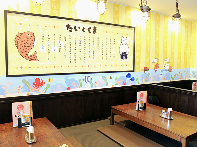 マスコットの「たい」と「くま」が描かれ、ポップでカラフルな店内。カウンター席や小上り席があり、1人でもグループでも利用しやすい