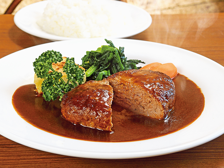 「ハンバーグ(160g)」(1,100円)、ライス(300円)。国産牛と豚の合い挽き肉を使用したボリューミーなハンバーグ。継ぎ足しで守ってきたデミグラスソースが肉のうまみを引き立てる
