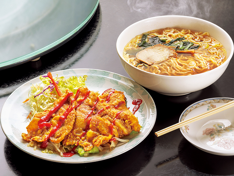 「サービスセット 豚ロースのカレー粉揚げ」（1,100円）。カリカリに揚げた豚ロースは、カレー風味で食欲をそそる。野菜炒めと生野菜も組み合わせた一皿。醤油ラーメン付き