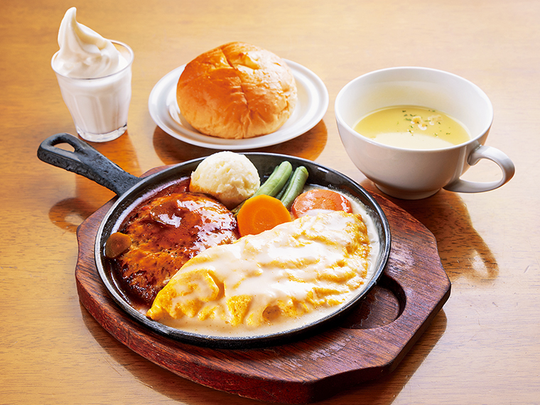 ランチメニュー(11時~15時、日曜祝日を除く)の一品「ハンバーグとチーズオムレツ」(980円)。デミグラスソースをかけたハンバーグは肉汁たっぷり。ふわとろチーズオムレツもポテトサラダも変わらないあの味。バターを乗せたパンまたはライス、スープ、コーヒーまたはフローズンヨーグルト付き