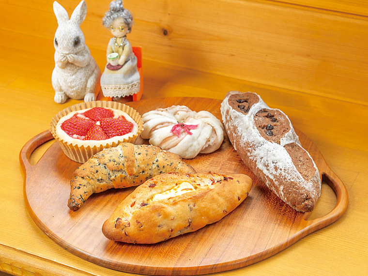 手前から時計回りに「クランベリーノア」(340円)、「黒ゴマ塩パン」(200円)、「ご飯でカスタードクリーム」(300円)、「桜のあんぱん」(200円※季節限定)、「チョコレートバケット」(430円※1日2本限定)。モチモチの生地が魅力の米粉パン。オーブントースターで2、3分焼いて食べるのがおすすめ