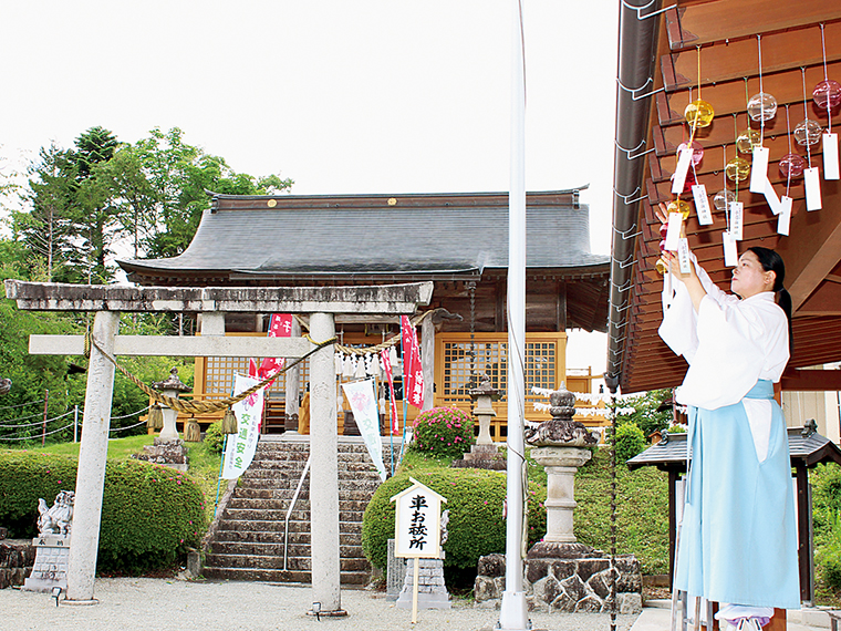 7月からの夏詣に合わせ、授与所の軒先に色とりどりの風鈴を飾る宮司・土屋友利恵さん