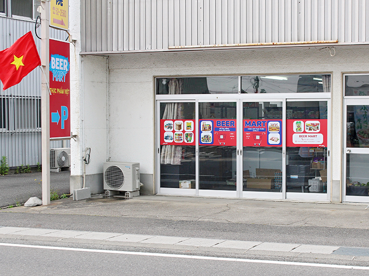 赤い看板と国旗が目印。店舗脇から入った共有駐車場を利用