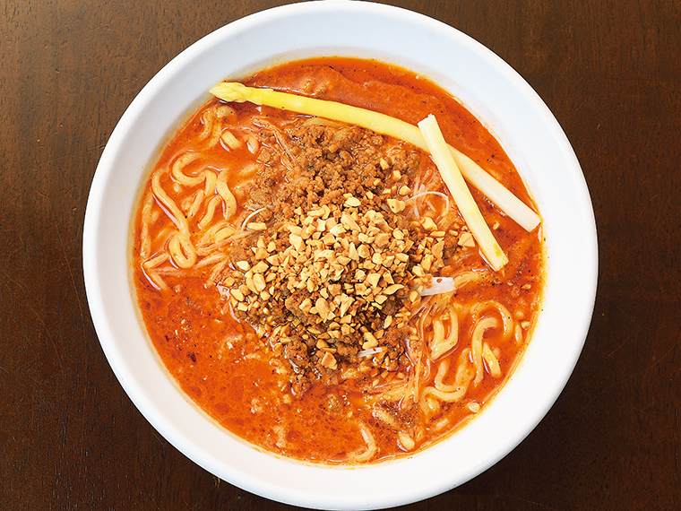 『塩川屋』の「ピーナッツ担々麺」(1,200円)。肉味噌の上にトッピングしたクラッシュピーナッツが食感のアクセントに。麺を食べ終えたらご飯を投入するのもおすすめ。辛さは好みで調整できる
