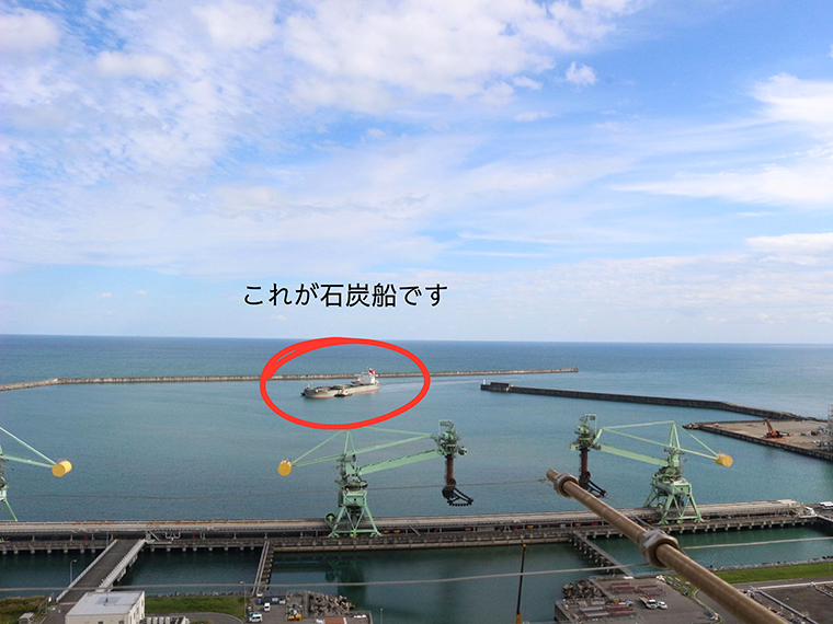 手前の緑のクレーンが石炭を取り出す楊炭機。湾内に石炭船が入港する様子