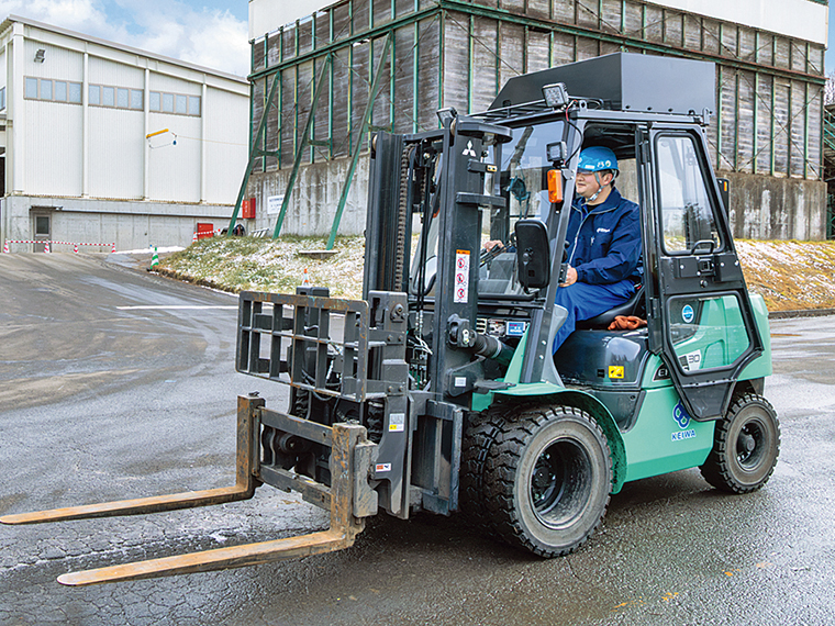 福島工場でコンテナを運ぶフォークリフトを操作する蓬田さん。各種重機の免許取得は、入社後に会社がサポートする
