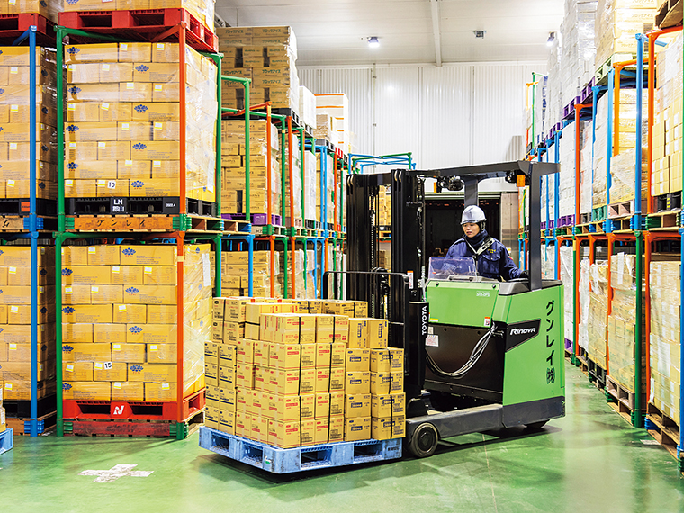 大量に荷が摘まれた倉庫の中、フォークリフトを自在に操り作業を行う。女性のフォークリフト資格保有者も複数在籍する