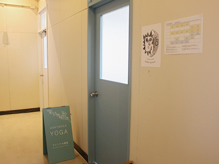 ビルの階段を上がって右に進むとスタジオがある。落ち着いた水色のドアと看板が目印