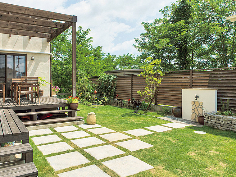 細部までこだわった外水道は、重厚な石積みの花壇とアンティークな蛇口が印象的。施主が用意したオブジェも一つひとつ丁寧に盛り込み、周囲の自然とも調和した庭先を実現。春から秋にかけて朱色やだいだい色の花が咲き並び、季節ごとに異なる景観を楽しめる