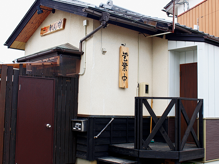 入口は、店名の看板が見える外壁から少し裏手に進む。営業中の看板が目印