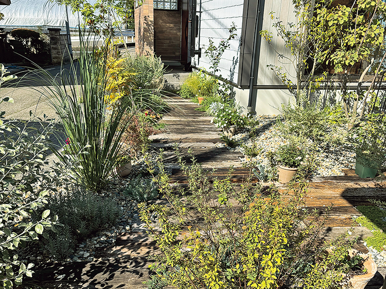 古材の枕木アプローチとたくさんの宿根草が玄関までの動線を豊かにする
