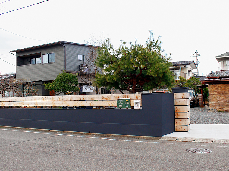 黒色と木目が特徴的な塀に囲まれ、砂利の中庭へ進むと駐車場がある