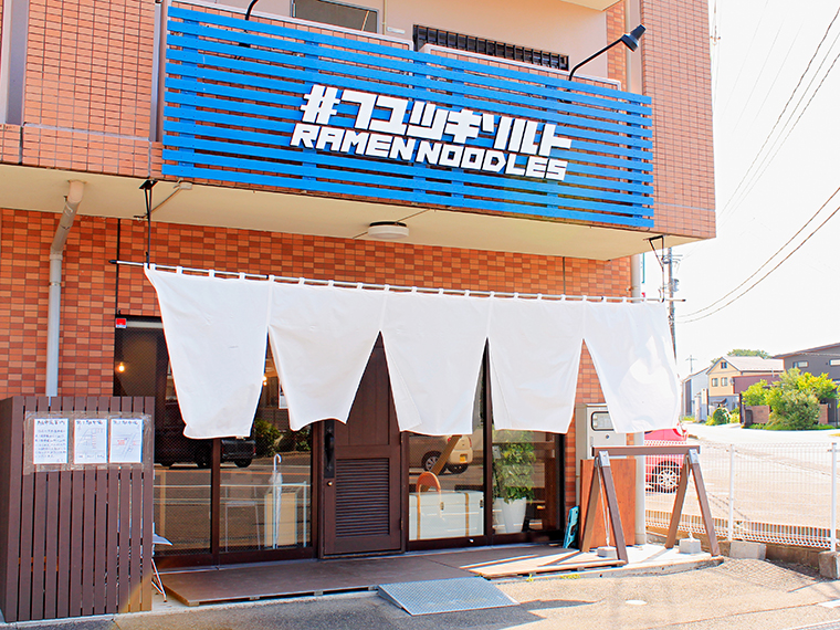 青色の看板が目印の店舗外観