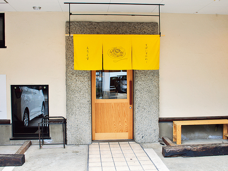 元居酒屋の名残を活かした入口。黄色ののれんが目印